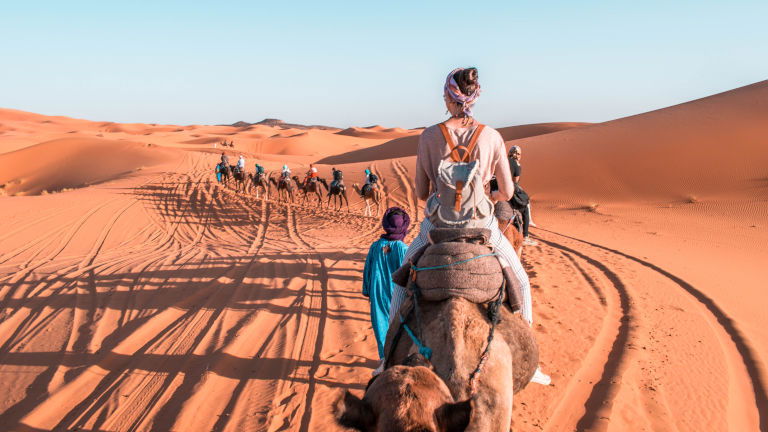Young traveller riding camel in Sahara, Morocco